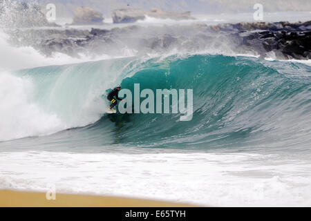 Eine lokale Surfer zieht in eine schwere, Ufer brechen Barrel im seichten Wasser an der Surf Break The Wedge in Newport Beach, Kalifornien Stockfoto