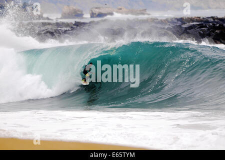 Eine lokale Surfer zieht in eine schwere, Ufer brechen Barrel im seichten Wasser an der Surf Break The Wedge in Newport Beach, Kalifornien Stockfoto