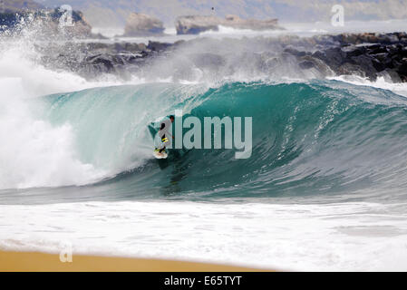 Eine lokale Surfer zieht in eine schwere, Ufer brechen Barrel im seichten Wasser an der Surf Break The Wedge in Newport Beach, Kalifornien Stockfoto