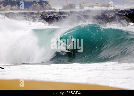 Eine lokale Surfer zieht in eine schwere, Ufer brechen Barrel im seichten Wasser an der Surf Break The Wedge in Newport Beach, Kalifornien Stockfoto