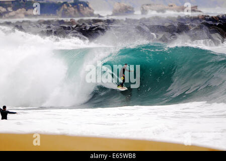 Eine lokale Surfer zieht in eine schwere, Ufer brechen Barrel im seichten Wasser an der Surf Break The Wedge in Newport Beach, Kalifornien Stockfoto