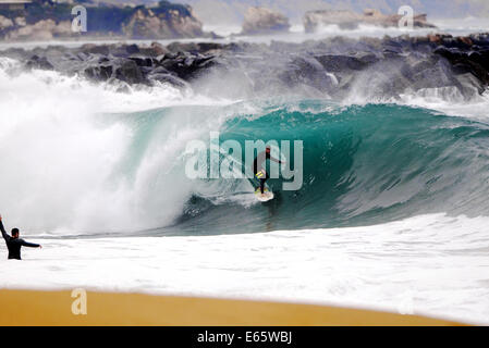 Eine lokale Surfer zieht in eine schwere, Ufer brechen Barrel im seichten Wasser an der Surf Break The Wedge in Newport Beach, Kalifornien Stockfoto