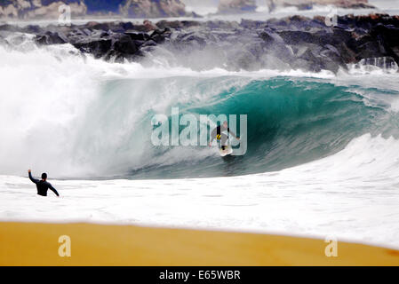 Eine lokale Surfer zieht in eine schwere, Ufer brechen Barrel im seichten Wasser an der Surf Break The Wedge in Newport Beach, Kalifornien Stockfoto