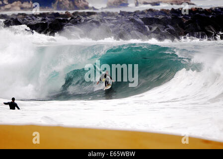 Eine lokale Surfer zieht in eine schwere, Ufer brechen Barrel im seichten Wasser an der Surf Break The Wedge in Newport Beach, Kalifornien Stockfoto