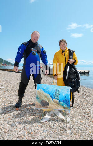 Unterwasser Künstler Yuriy Alexeev (Yuri Alekseev) und sein Assistent stehen neben dem Bild gemalt im Wasser. Stockfoto