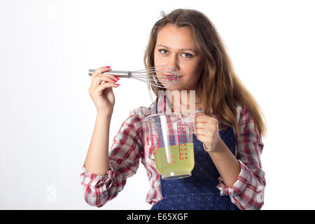 Junge Brünette weibliche Köchin bereitet mit Küchenutensilien spielerisch Lebensmittel zu Stockfoto