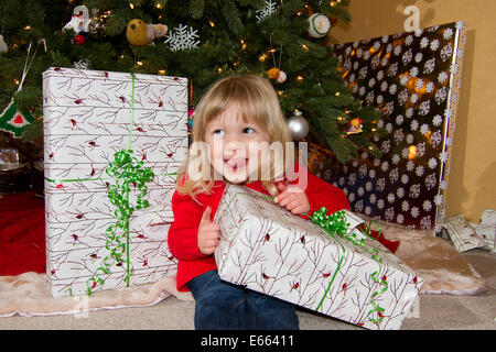 Ein niedliche kleine kaukasische Mädchen begeistert über ihr Weihnachten präsentiert. Stockfoto