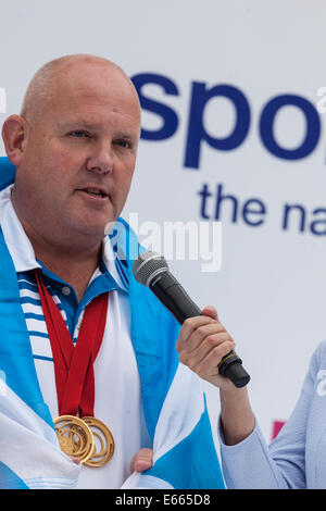 Glasgow, Schottland, Großbritannien. 15 Aug, 2014. Alex "Tattie' Marshall, MBE, Boccia Doppel Gold medallist und Team Schottland Fahnenträger in Glasgow Abschlussfeier 2014 in George Square am Ende der Parade, befragt Team Schottland zu grüßen nach den Commonwealth Games. Alex Marshall gewann Gold in der Männer Paare und vieren der Männer Veranstaltungen im Lawn Bowls. Er hat die Welt innen Titel Singles fünf Mal, und hat eine Aufzeichnung 19 Welt Titel statt. Er war als 2014 die schottischen Sportler des Jahres bekannt gegeben. Stockfoto