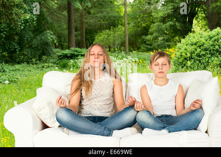Jungen und Mädchen meditieren im Wald Stockfoto