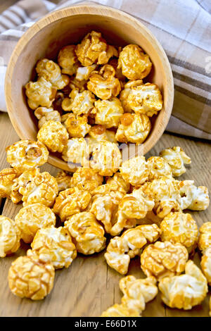 Karamell Popcorn gegossen aus Holzschalen, Serviette auf dem Hintergrund der Holzbretter Stockfoto
