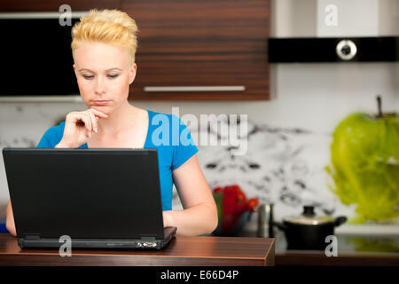Frau Post auf Laptop in der Küche zu Hause überprüfen Stockfoto