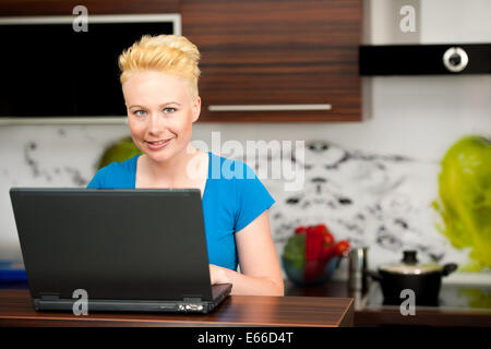 Frau Post auf Laptop in der Küche zu Hause überprüfen Stockfoto