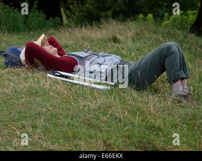 Asiatische Frau, die eine Siesta auf dem Rasen in Avebury, Wiltshire, UK Stockfoto