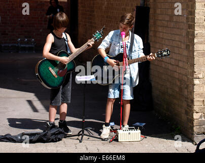 Zwei Kinder als Straßenmusikant auf den Straßen von Cirencester, Gloucestershire, UK Stockfoto