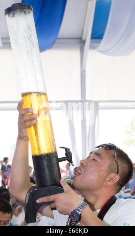 Qingdao, China. 16. August 2014. Ein Mann trinkt ein Bier am 24. Oktoberfest in Qingdao, China, 16. August 2014. Laut Veranstalter ist es zum größten Volksfest in Asien. Foto: FRISO GENTSCH/Dpa/Alamy Live News Stockfoto