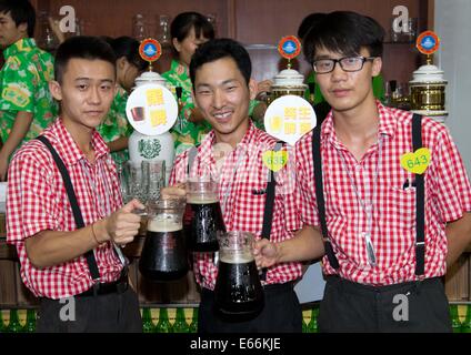 Qingdao, China. 16. August 2014. Kellner tragen Becher Bier während 24. Oktoberfest in Qingdao, China, 16. August 2014. Laut Veranstalter ist es zum größten Volksfest in Asien. Foto: FRISO GENTSCH/Dpa/Alamy Live News Stockfoto