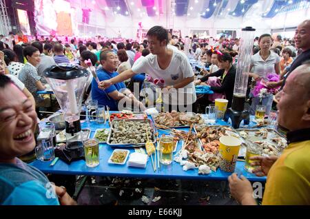 Qingdao, China. 16. August 2014. Menschen essen Meeresfrüchte 24. Oktoberfest in Qingdao, China, 16. August 2014. Laut Veranstalter ist es zum größten Volksfest in Asien. Foto: FRISO GENTSCH/Dpa/Alamy Live News Stockfoto