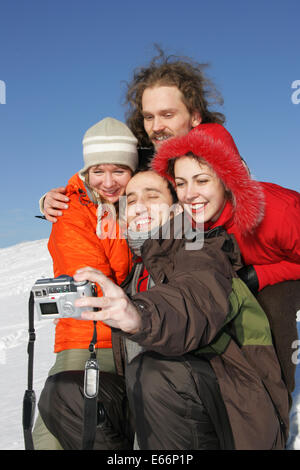 Vier Freunde, die unter einem Selbstbildnis im winter Stockfoto