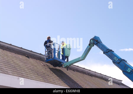 Zwei Männer arbeiten auf einem Dach aus einer Access-Plattform Stockfoto