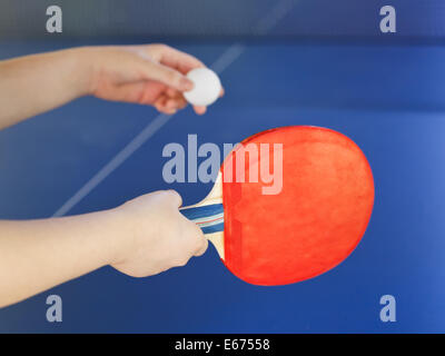 Mädchen spielt im Tischtennis mit roten Schläger auf blauen Ping-Pong-Tisch hautnah Stockfoto