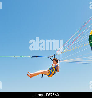 Mädchen am Fallschirm in blauen Himmel im Sommertag parasailing Stockfoto