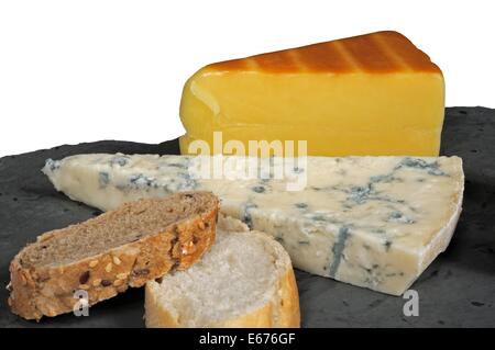 Irischer Räucherlachs Cheddar und italienischer Gorgonzola mit Brot auf einem Stück des walisischen Schiefer vor einem weißen Hintergrund. Stockfoto