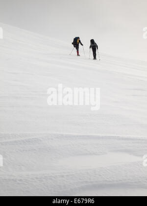 zwei Männer mit schweren Rucksäcken ein Berghang mit Schneeschuhen im Winter klettern. Huldraheimen, Gausdal Westfjel, Norwegen Stockfoto