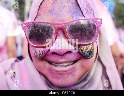 Kuala Lumpur, Malaysia.  17. August 2014. Ein Teilnehmer lächelt mit Gesicht bedeckt mit bunten Pulver, nachdem sie ihr Lauf während CIMB Color Run am 17. August 2014 in Kuala Lumpur beendet. Color-Run, auch bekannt als der glücklichste 5 k zum ersten Mal in Malaysia statt zieht Tausende von Läufern aus verschiedenen Gruppe, Alter und ethnische. Bildnachweis: Kamal Sellehuddin/ZUMA Draht/Alamy Live-Nachrichten Stockfoto
