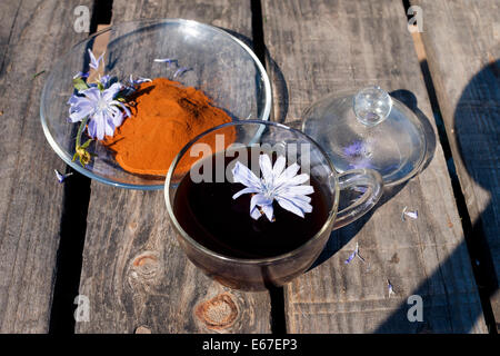 Chicoree-Pulver auf Teller mit Chicorée Blumen und Chicorée trinken im Cup auf hölzerne Schreibtische Stockfoto