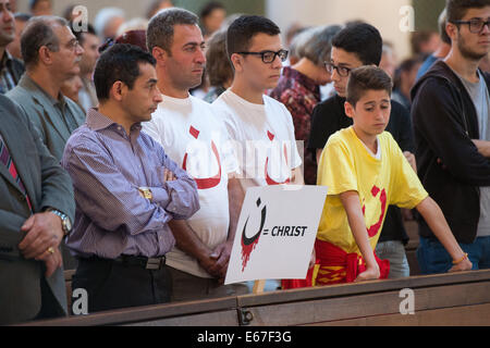 Berlin, Deutschland. 17. August 2014. Gläubigen nehmen Teil in einem ökumenischen Gottesdienst für die verfolgten Christen im Irak und in Syrien in der St. Hedwig Cathedral in Berlin, Deutschland, 17. August 2014. Sie halten ein Schild mit der Aufschrift 'Christ' neben dem arabischen Buchstaben ' n ' für 'Nasara', d.h. Christen). Dies ist das Symbol, das Mitglieder der islamischen Miliz (IS) verwenden, um die Häuser von Christen in Mossul im Norden des Irak zu markieren. Foto: Maurizio Gambarini/Dpa/Alamy Live News Stockfoto