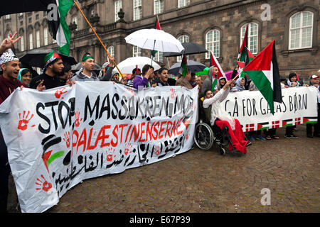 Kopenhagen, Dänemark. 17. August 2014. Trotz des strömenden Regens versammeln sich Hunderte von Copenhagener in einem Frieden Match zur Unterstützung von Kindern im Gaza-Streifen und gegen den israelischen Krieg in ihrem Land. Der Friedensmarsch endete vor dem dänischen Parlament, Christiansborg, nach 2 Stunden lang zu Fuß durch die Stadt. Die beiden Zeichen lesen in Englisch: (links) "Stop dem Massaker gegen die Palästinenser" und (rechts) "Walk für Gaza Kinder" Credit: OJPHOTOS/Alamy Live News Stockfoto