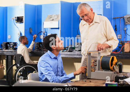 Schüler, die Einrichtung von Generator-Experiment mit Professor während Student im Rollstuhl HVAC-System untersucht Stockfoto