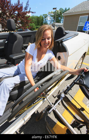 Frau mit Verletzungen des Rückenmarks ziehen Rad vom Rollstuhl in ihrem adaptiven Fahrzeug Stockfoto