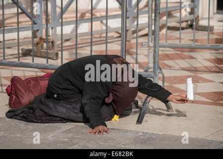 Eine Frau kniet und beugt beim betteln in Piazza San Marco in Venedig. Stockfoto