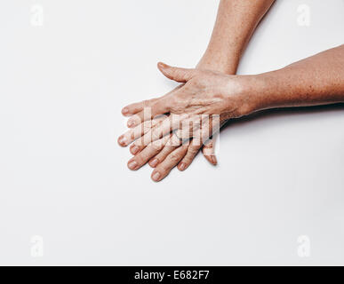 Draufsicht der alte weibliche Hände mit Fingern überqueren. Ältere Frau Hände isoliert auf weißem Hintergrund mit Textfreiraum. Stockfoto