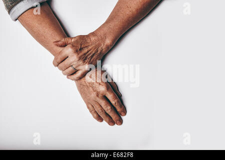 Draufsicht auf eine ältere Frau Hände ruhen auf grauem Hintergrund. Entspannt, alte weibliche Hände zusammen. Stockfoto