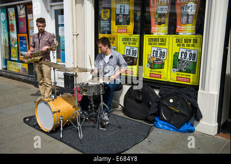 Saxophon & Schlagzeug-Duo Straßenmusikanten auf der Straße vor Schnäppchen Alkohol während Brecon Jazz Festival 2014 Stockfoto