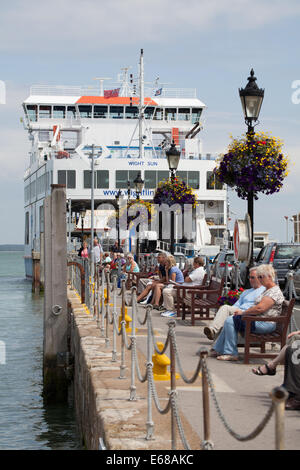 Yarmouth nach Lymington Autofähre vertäut mit Menschen sitzen am Kai auf Bänken an einem Sommertag Stockfoto