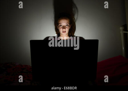 Computer Laptop verwendet wird, von einem Kind in ihr Schlafzimmer, teenage Girl mit einem Computer Laptop allein in ihrem Zimmer Stockfoto