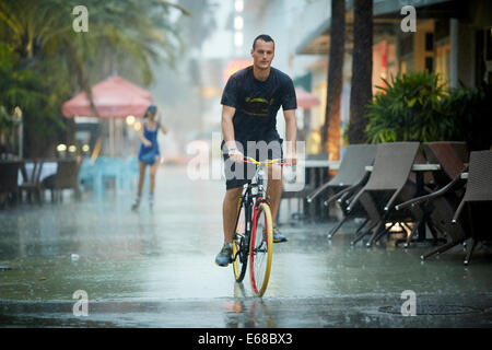 Ein Mann durchläuft die Straße auf seinem bunten Fahrrad Stockfoto