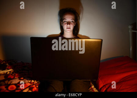 Computer Laptop verwendet wird, von einem Kind in ihr Schlafzimmer, teenage Girl mit einem Computer Laptop allein in ihrem Zimmer Stockfoto