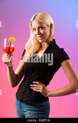 Schöne junge Frau trinken Aperol Spritz über farbigen Hintergrund isoliert Stockfoto