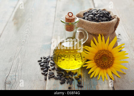 Sonnenblumenöl in Flaschen mit Samen und Blumen auf hölzernen Hintergrund Stockfoto