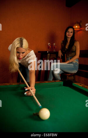 Schöne junge Blondine in einer Bar Billard spielen Stockfoto