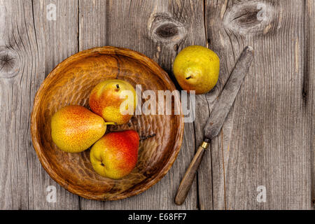 Birnen auf einer Holzplatte mit einem Messer auf einem alten rustikalen Holztisch im Landhausstil Stockfoto