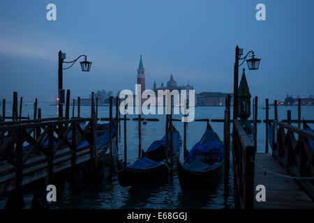 Morgendämmerung am Ufer von Venedig mit Gondeln Blick in Richtung der Kirche San Giorgio Maggiore über die Lagune. Stockfoto