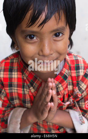 Ein Junge, lächelnde Hindu Kind mit gefalteten Händen (eine "Namaste") auf den Straßen von Kathmandu, Hauptstadt von Nepal. Stockfoto