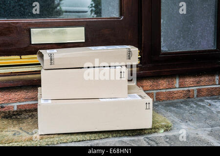 Eine Reihe von Amazon Kartons links ein Haus vor der Tür. Stockfoto