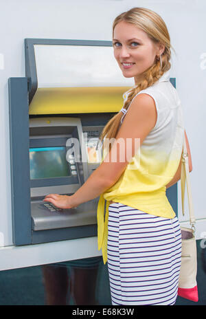 Hübsche Frau an einem Geldautomaten Geld abheben. Stockfoto