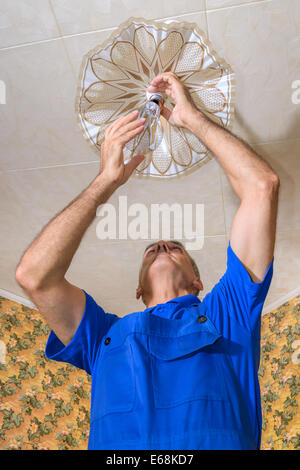 Die Elektriker ersetzt eine Glühbirne in einem Leuchter Stockfoto